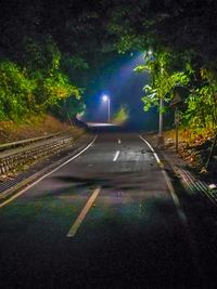 Illuminated road against sky at night