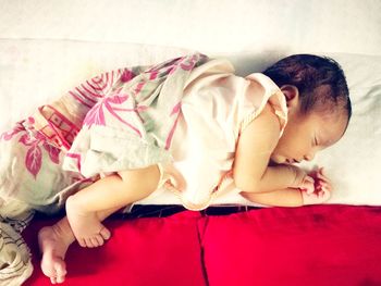 Close-up of baby girl on bed at home