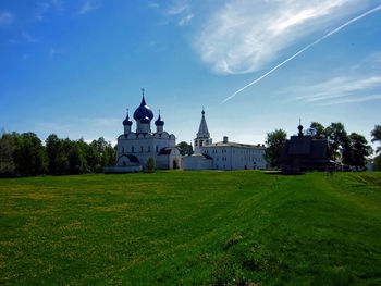 Church on field by building against sky