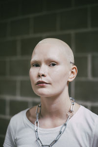 Portrait of young woman standing against wall