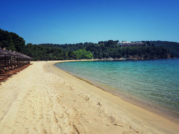 Scenic view of beach against clear blue sky