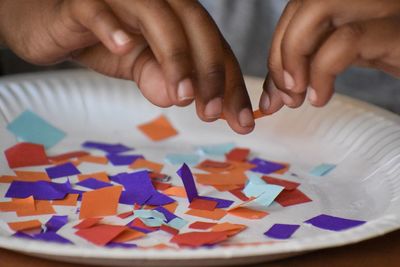 Close-up of cropped hands holding paper in plate