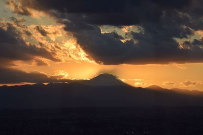 Scenic view of silhouette mountains against orange sky