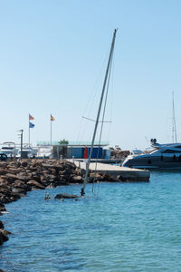 Sailboats moored in sea against clear sky