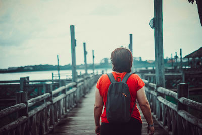 Rear view of woman standing on bridge against sky