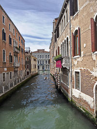 Canal amidst buildings in city against sky