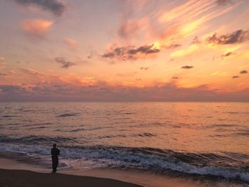 Silhouette person on beach against sky during sunset