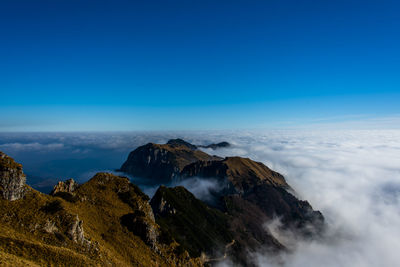 Clouds and alpine peaks with pine trees and rocks in the clouds around recoaro, vicenza, italy