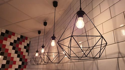 Low angle view of illuminated pendant light hanging on ceiling