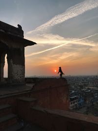 People standing by building against sky during sunset