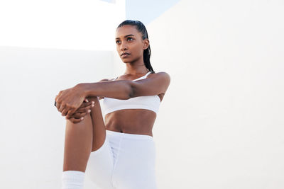 Portrait of young woman exercising against white background