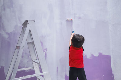 Rear view of boy painting wall