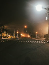 Illuminated city street against sky at night