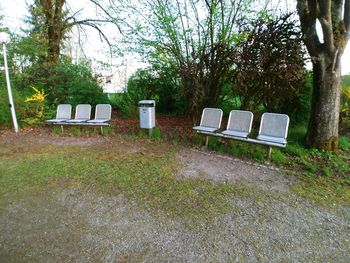 Empty chair on field against trees in park