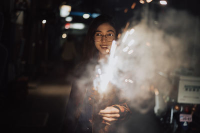 Portrait of smiling woman standing at night