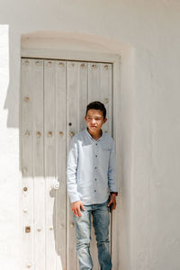 Portrait of smiling young woman standing against door