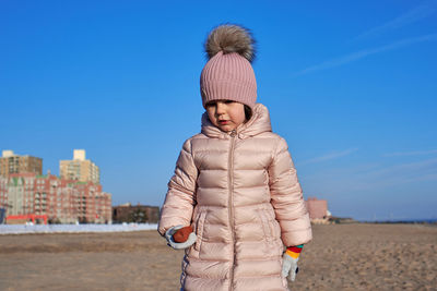 Young girl playing on the beach in winter dressed in a warm coat