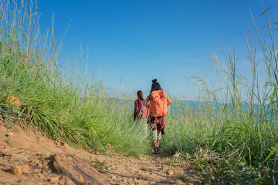 Rear view of man walking on land against sky