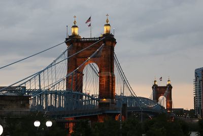 Low angle view of suspension bridge against cloudy sky