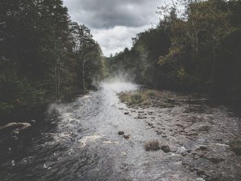 Scenic view of waterfall in forest against sky