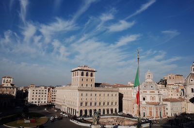 Italian flag and buildings in city against blue sky on sunny day