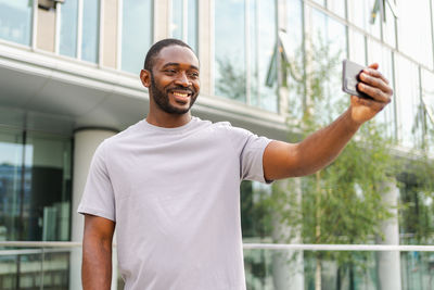 Portrait of young man standing against window