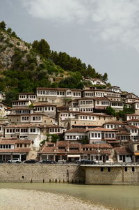 Residential buildings by river against sky