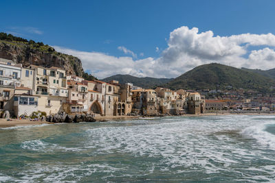 Buildings by sea against sky