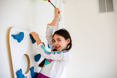 Portrait of smiling girl standing against wall