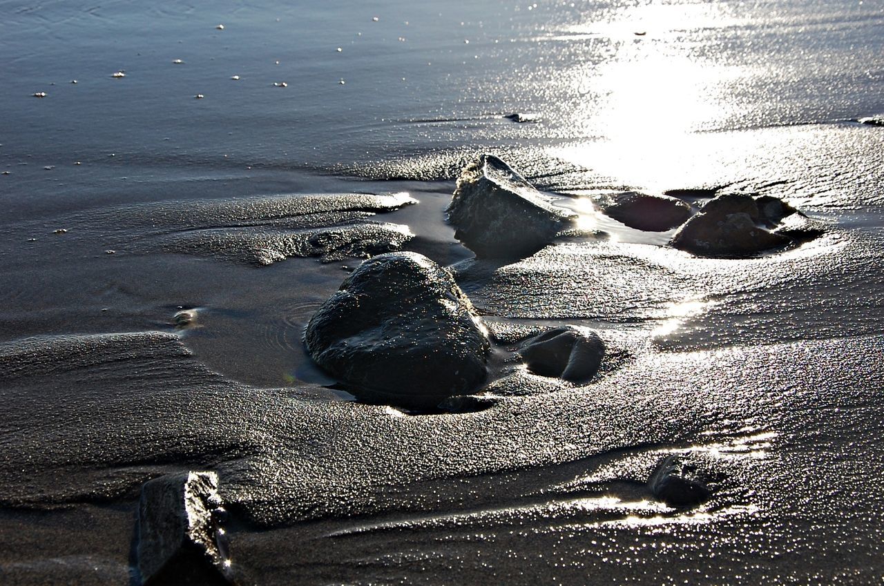 beach, sea, water, shore, sand, tranquility, nature, sunlight, pebble, beauty in nature, stone - object, horizon over water, seashell, tranquil scene, outdoors, rock - object, wet, day, high angle view, scenics