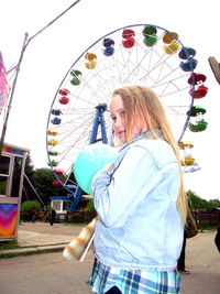 Low angle view of woman in amusement park against clear sky