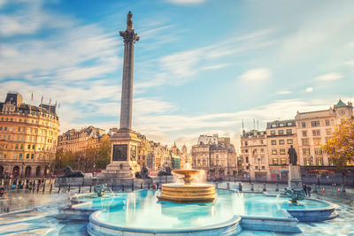 Water fountain against city buildings and sky