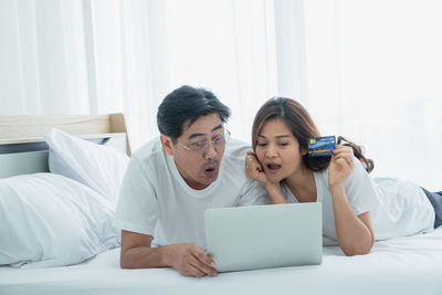 Young man using mobile phone while sitting on bed