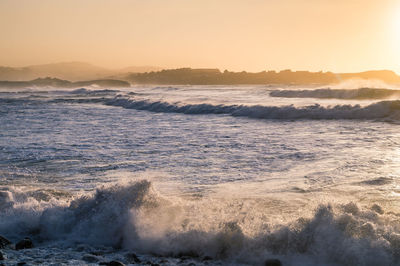 Waves rushing towards shore during sunset