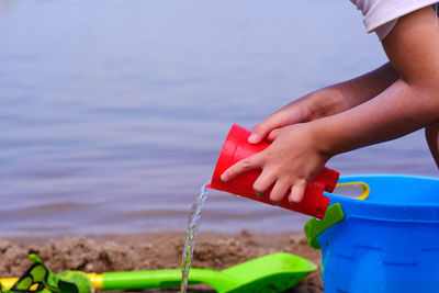 Close-up of hand holding toy against sea