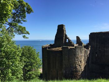 Castle by sea against clear blue sky