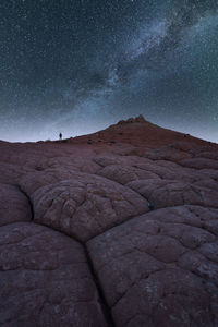 Silhouette of unrecognizable explorer standing on scenery of rocky formations in highlands under milky way starry sky in vermillion cliffs national monument, arizona in usa