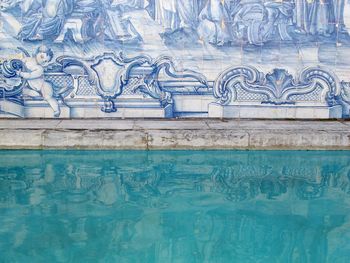 Mosaic painting on wall with reflection in swimming pool