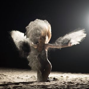 Mid adult woman dancing on sand at night