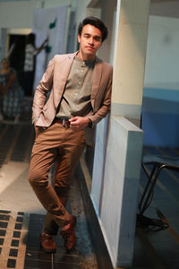 Portrait of young man standing against wall