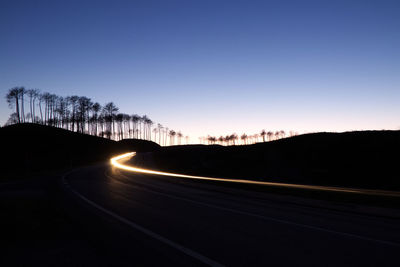 Light trails on road against clear sky at night