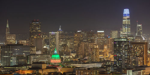 Illuminated buildings in city against sky at night