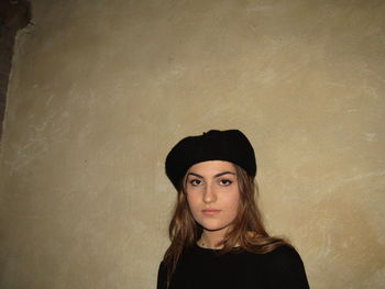 Portrait of young woman standing against wall