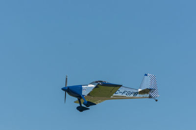 Low angle view of airplane flying against clear blue sky