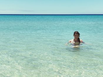 Full length of man relaxing in sea against sky