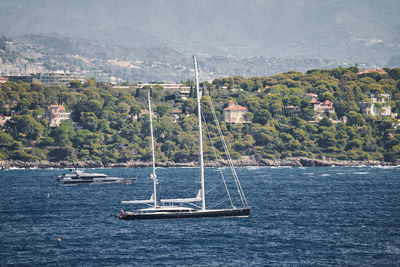 Sailboat sailing on sea against mountain