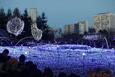 Crowd at music concert against sky at night