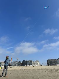 Low angle view of child flying a kite against sky