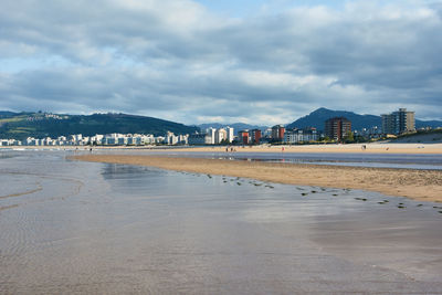 Scenic view of beach by city against sky