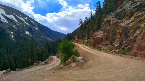 Scenic view of dirt road passing through mountains